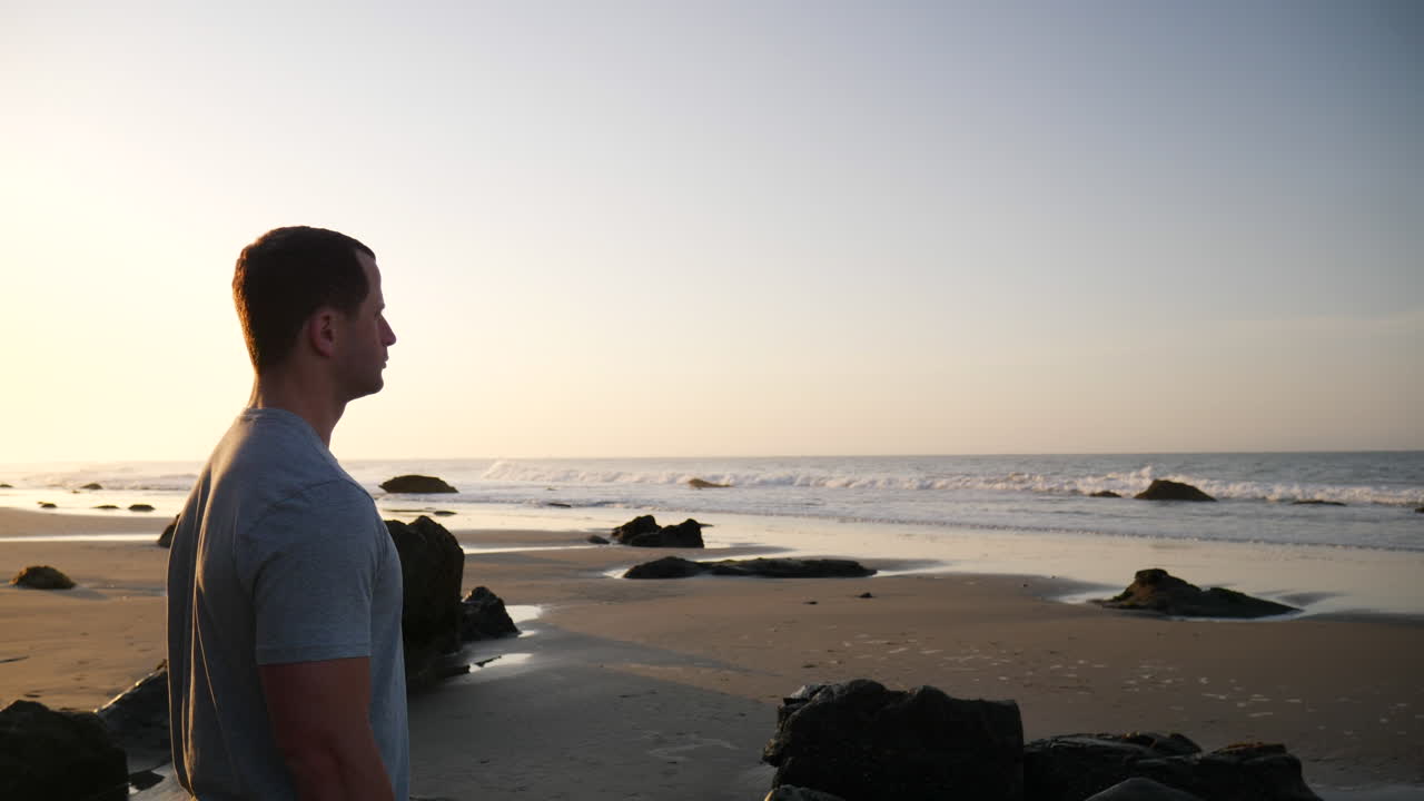 바다의 파도를 보고 캘리포니아 산타바바라의 일출 해변에서 아침 운동을 준비하는 강하고 잘 생긴 남자