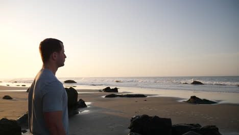 a strong good looking man watching the ocean waves and preparing for a morning workout on the beach at sunrise in santa barbara, california slow motion