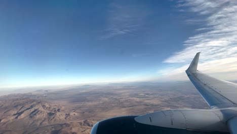 shot of airplane window seat with wing and turbine during landing