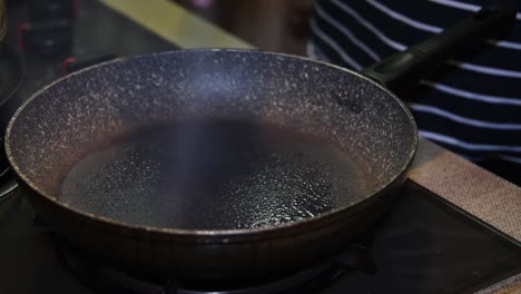 frying pan getting sprayed with olive oil