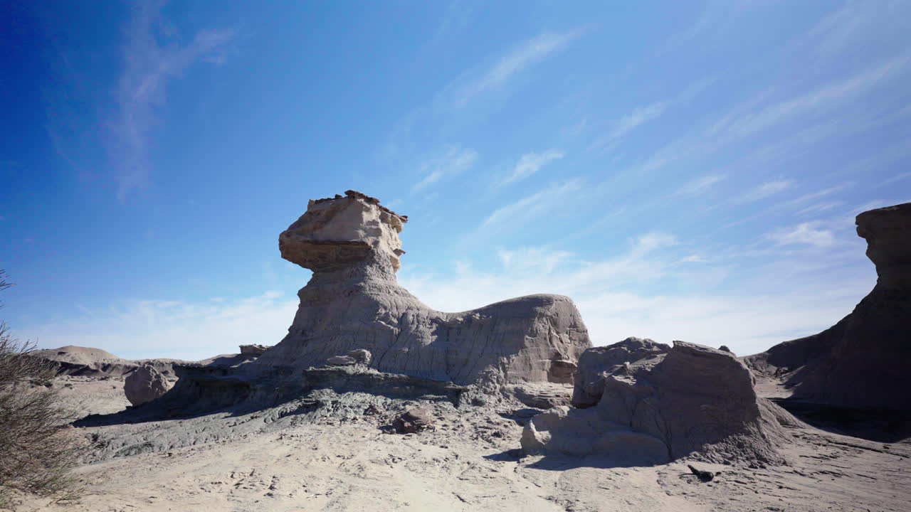 Slow panning shot shows sphinx-shaped rock formation under a bright sun, showcasing faded desert colors