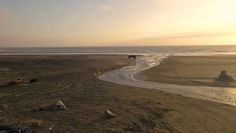 four wheel off-road vehicle driving on the beach in the late afternoon, crossing a stream