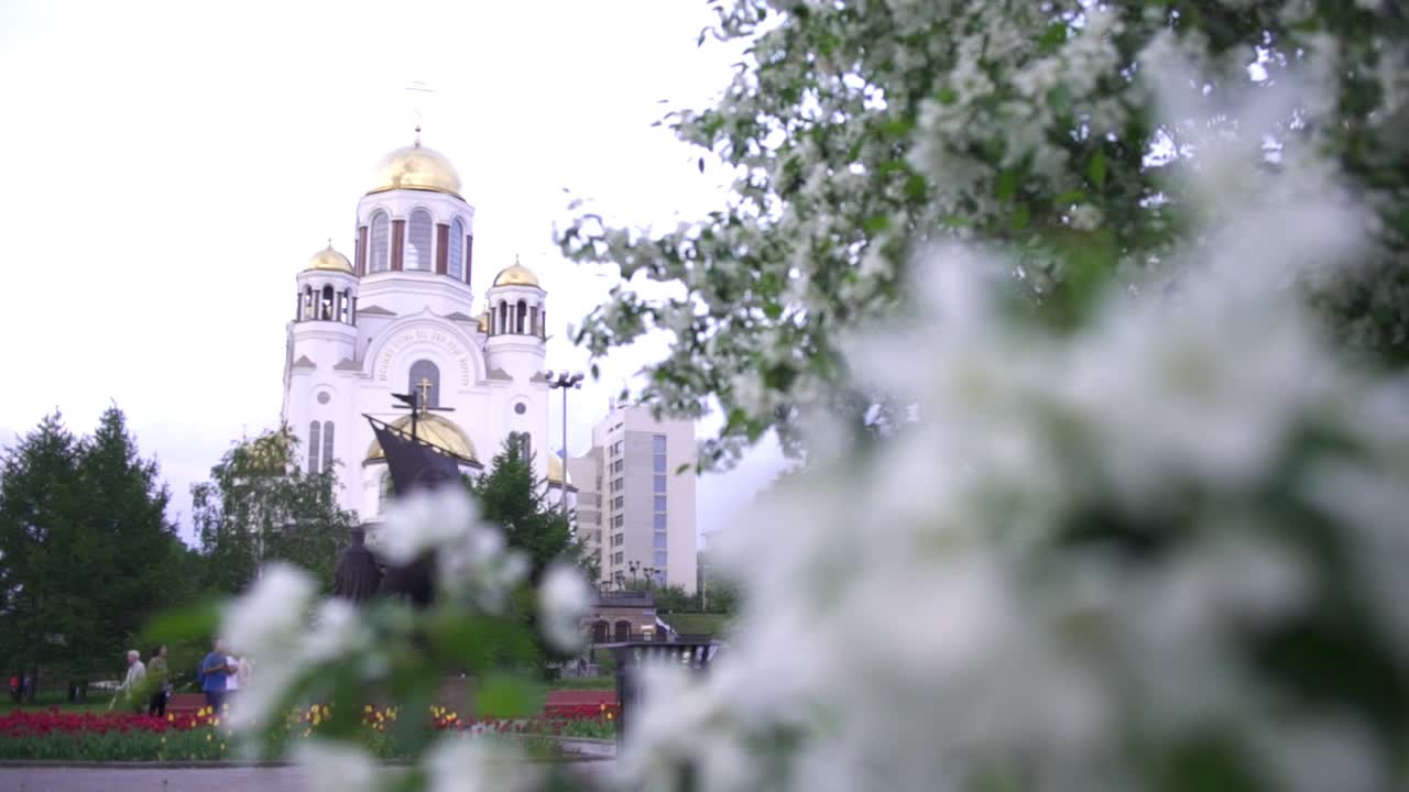 iglesia ortodoxa y flores en un parque de la ciudad