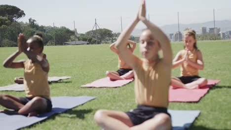 focused diverse elementary school schoolgirls practicing yoga at stadium in slow motion