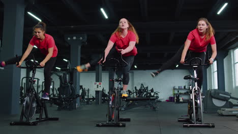 healthy caucasian group of women exercising workout on stationary cycling machine bike in gym