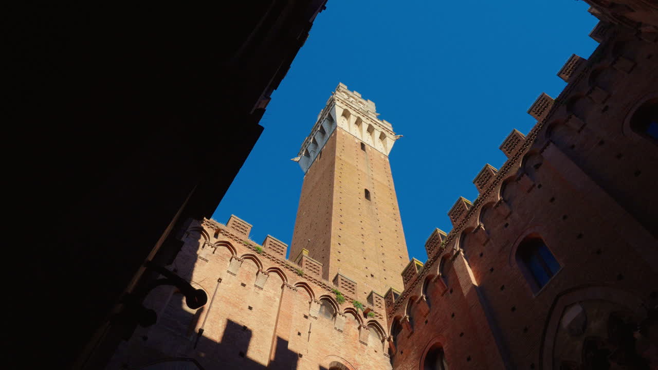 Upward shot of Siena's Mangia Tower on a sunny day in Italy