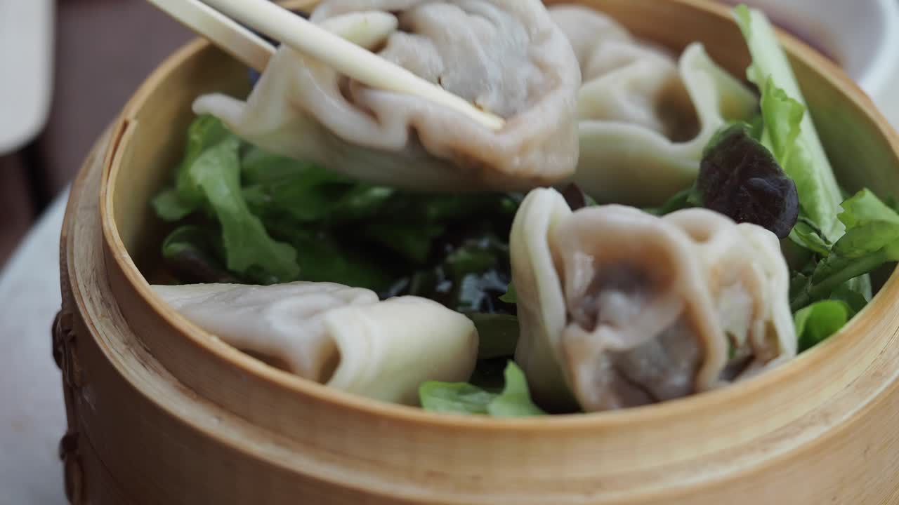 Chopsticks Picking Up Steamed Dumplings from Bamboo Basket