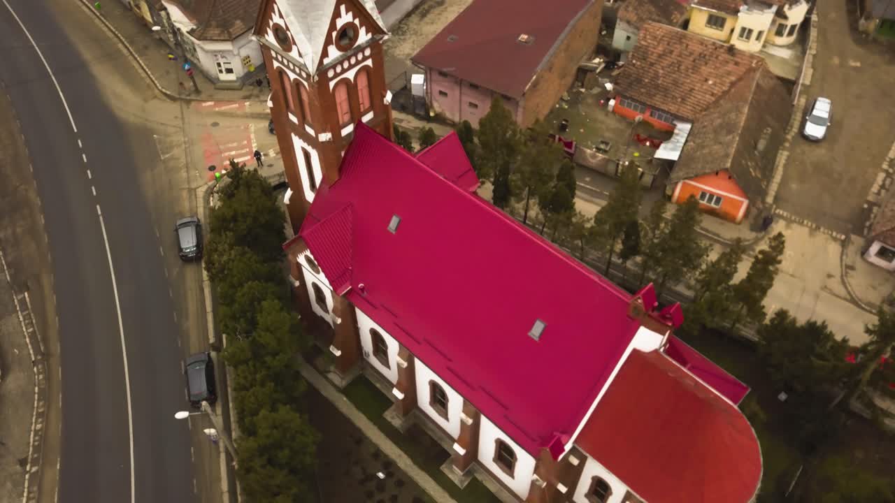 Close-up e sobrevoo de drone aéreo de uma igreja com telhado vermelho numa pequena vila comunitária no interior da província da Romênia
