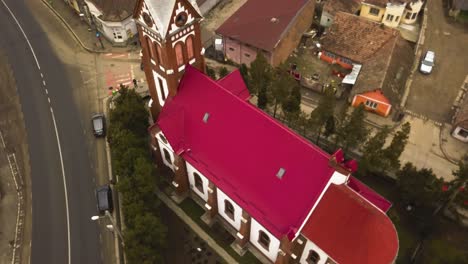 Un-Dron-Aéreo-Se-Acerca-Y-Sobrevuela-La-Iglesia-De-Techo-Rojo-En-Un-Pequeño-Pueblo-Comunitario-En-La-Provincia-De-Rumania