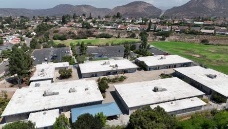 Vista-Orbital-Aérea-Del-Edificio-Y-Patio-De-La-Escuela-Primaria-Ralph-Dailard,-Comunidad-De-San-Carlos-San-Diego-California,-Patio-De-Recreo-Verde,-Rodeado-Por-El-Vecindario-Y-La-Montaña-Cowles