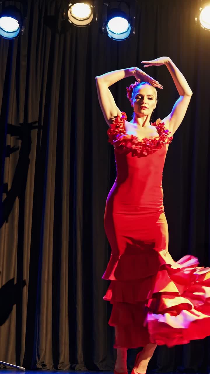 Un video dinamico ad angolazione laterale cattura un ballerino in un vivace abito rosso da flamenco, illuminato sul palco