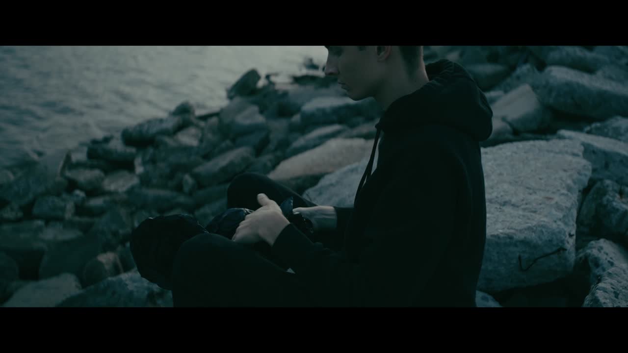 Person Sitting on Rocks by the Water