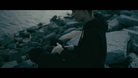 person sitting on rocks by the water