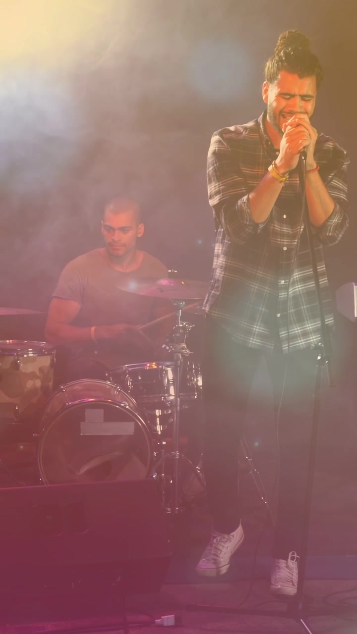 Video verticale: Batterista che inizia il ritmo, cantante che afferra il microfono, canta avvolto dalla musica per coinvolgere la folla.