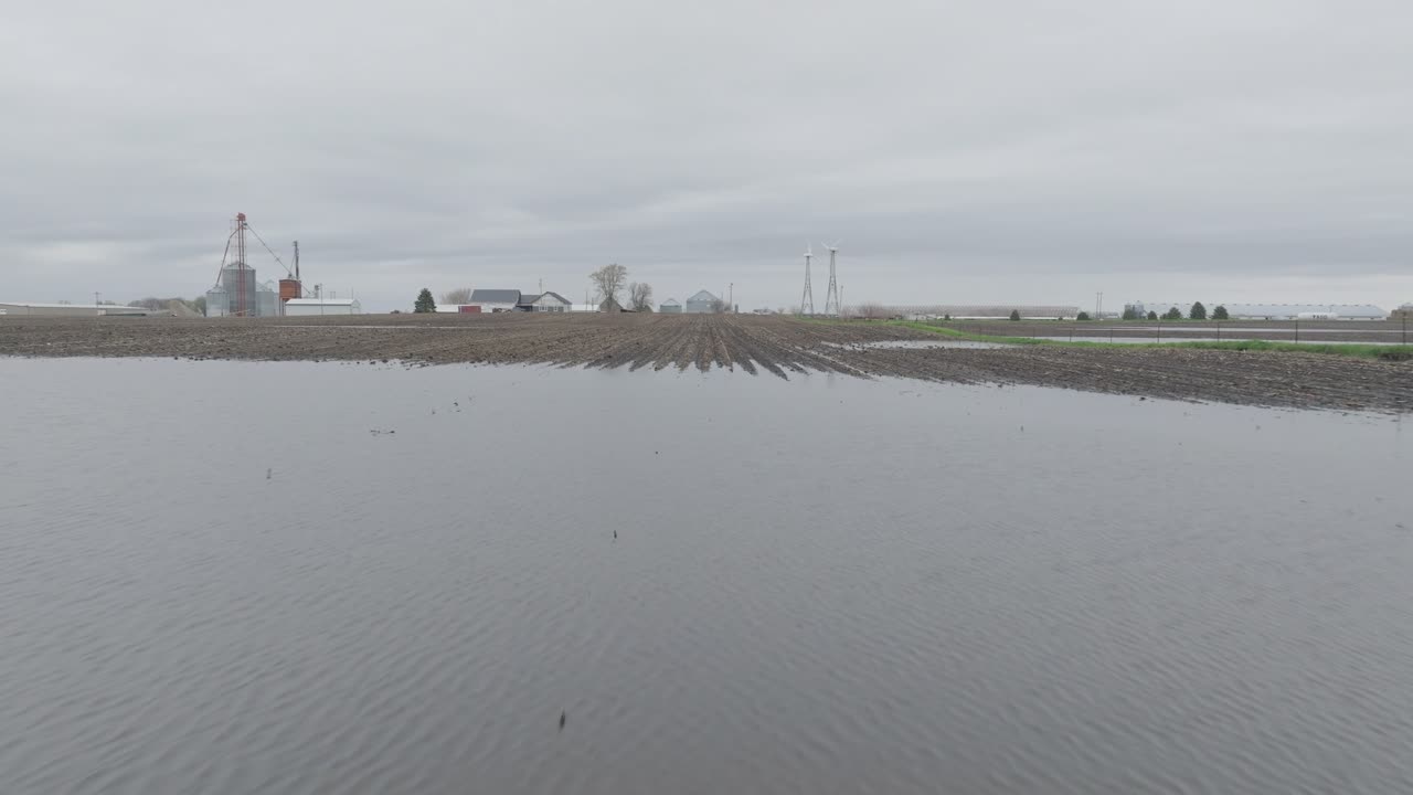Flying Over The Flooded And Muddy Fields Towads The Silos In The Early Morning. - aerial shot