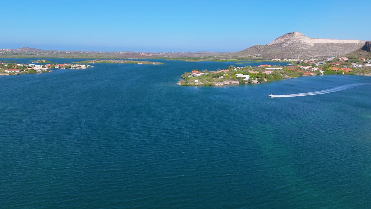 Aerial view of a boat speeding across a calm ocean near a tropical island