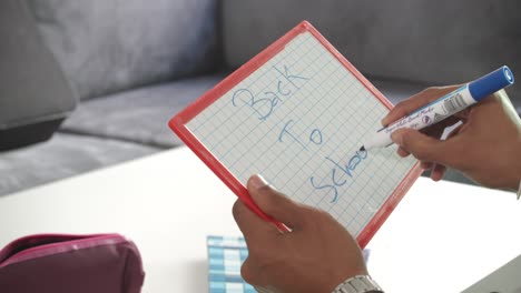 Rechtshändiger-Schüler-Schreibt-Auf-Einem-Gerasterten-Whiteboard-Mit-Blauem-Marker-Zurück-In-Die-Schule