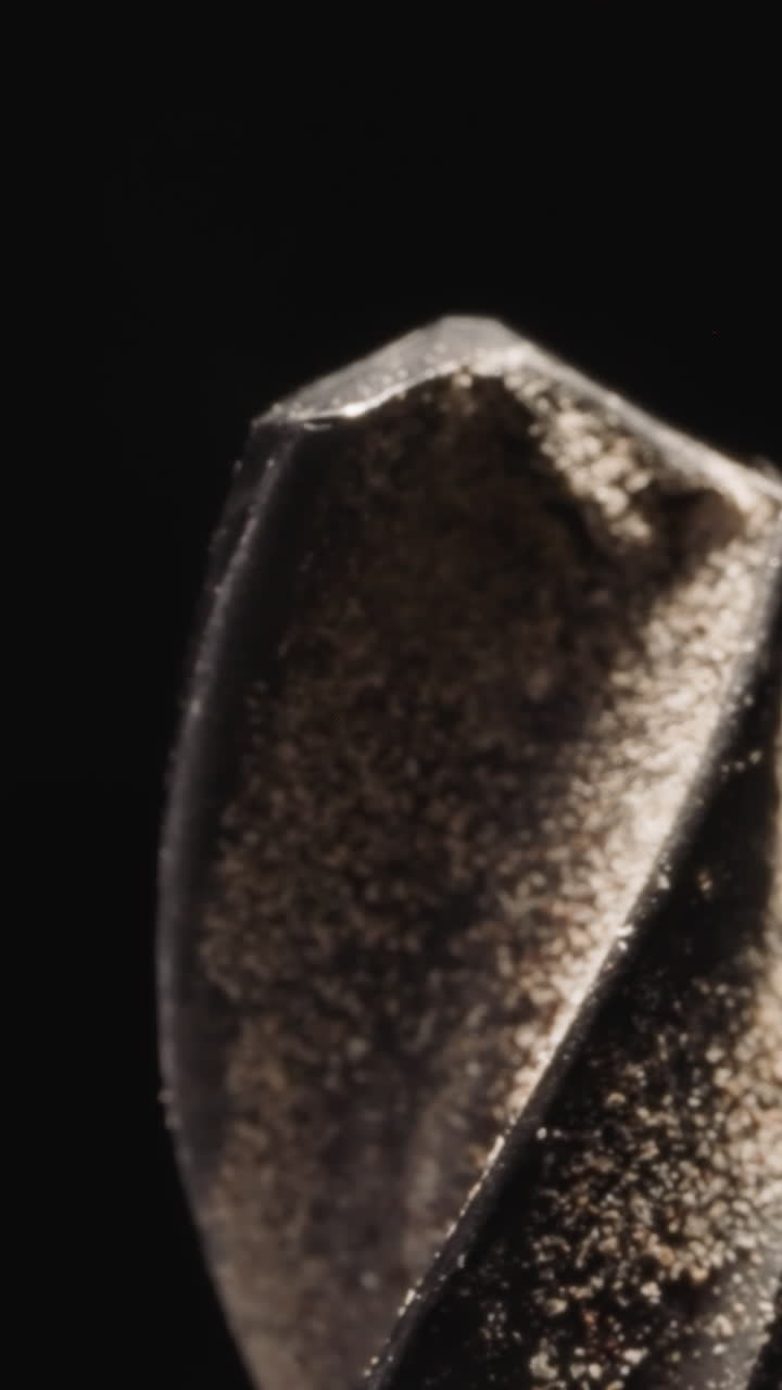 Drill tip for working with wood covered with shavings on black background. Professional instrument for woodwork at bright studio light macro