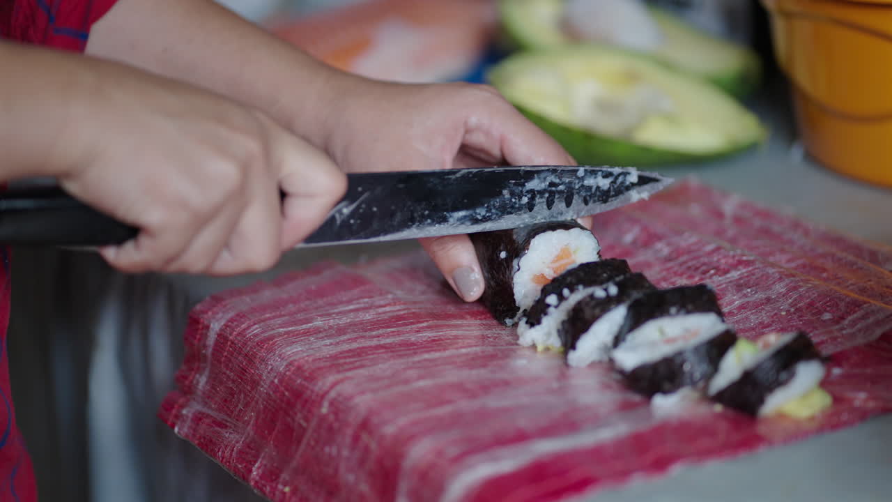 Woman Cutting Salmon Maki Into Bite-Sized. - closeup shot