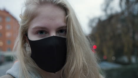 Close-up,-turning-around-blonde-woman-with-black-face-mask,-slow-motion