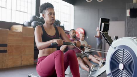 Focused-african-american-woman-training-on-rowing-machine-at-gym,-in-slow-motion