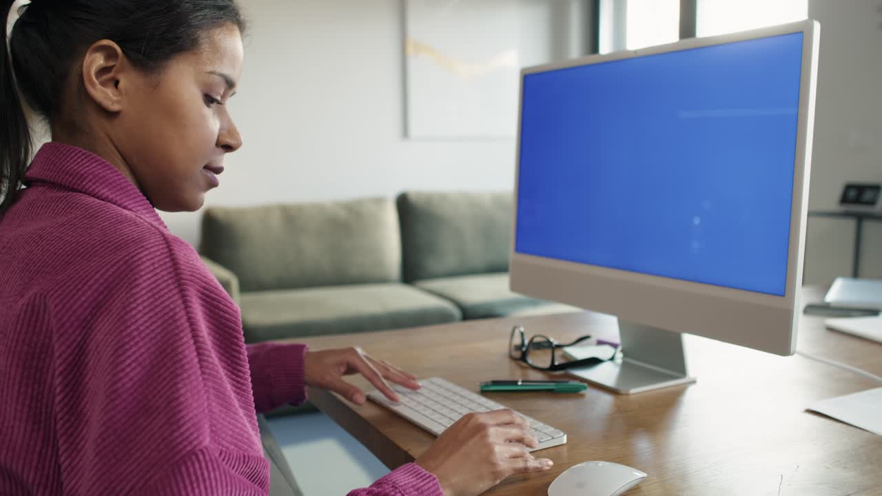 vista lateral de una mujer trabajando en una computadora con pantalla azul