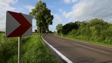 Motorcyclist-riding-on-a-curved-country-road-with-directional-signs-on-a-sunny-day