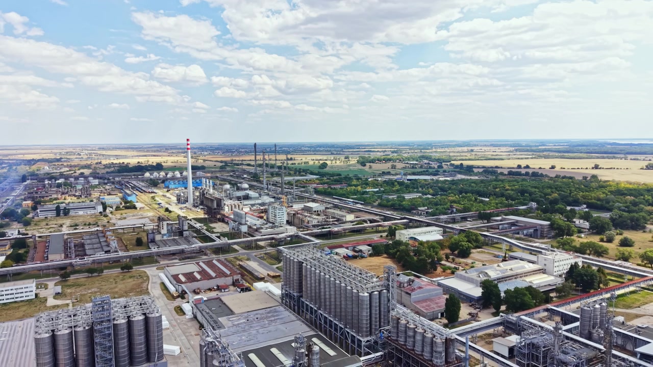 Gran zona industrial con fábricas y campos bajo un cielo nublado durante el día.