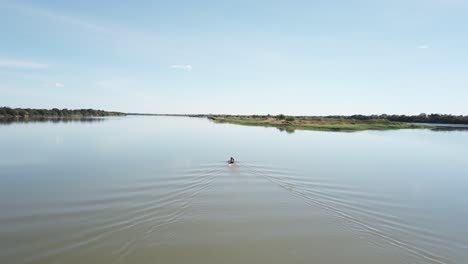 Toma-Aérea-Amplia-Siguiendo-Un-Pequeño-Barco-De-Pesca-En-El-Río-Sao-Francisco-En-Las-Zonas-Rurales-De-Brasil