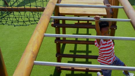 high angle view of african american schoolboy playing on horizontal ladder in school playground 4k