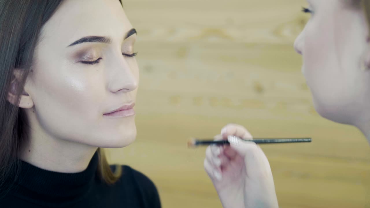artista de maquillaje de bodas haciendo maquillaje para la novia. hermosa modelo sexy chica en el interior. mujer de belleza con cabello rizado. retrato femenino. mañana de novia de una dama linda. manos de primer plano cerca de la cara