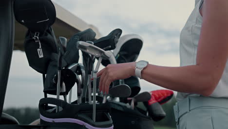 Woman-prepare-golf-equipment-bag-on-course.-Lady-hands-take-clubs-on-sport-game.