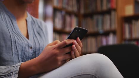 Asian-female-student-wearing-a-blue-hijab-sitting-and-using-a-smartphone