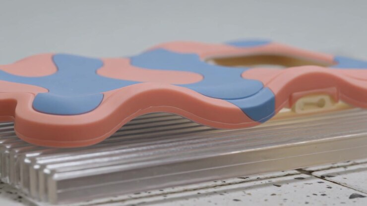 Panning camera revealing pink-blue case on tray at studio tabletop, showing beige latch, layers