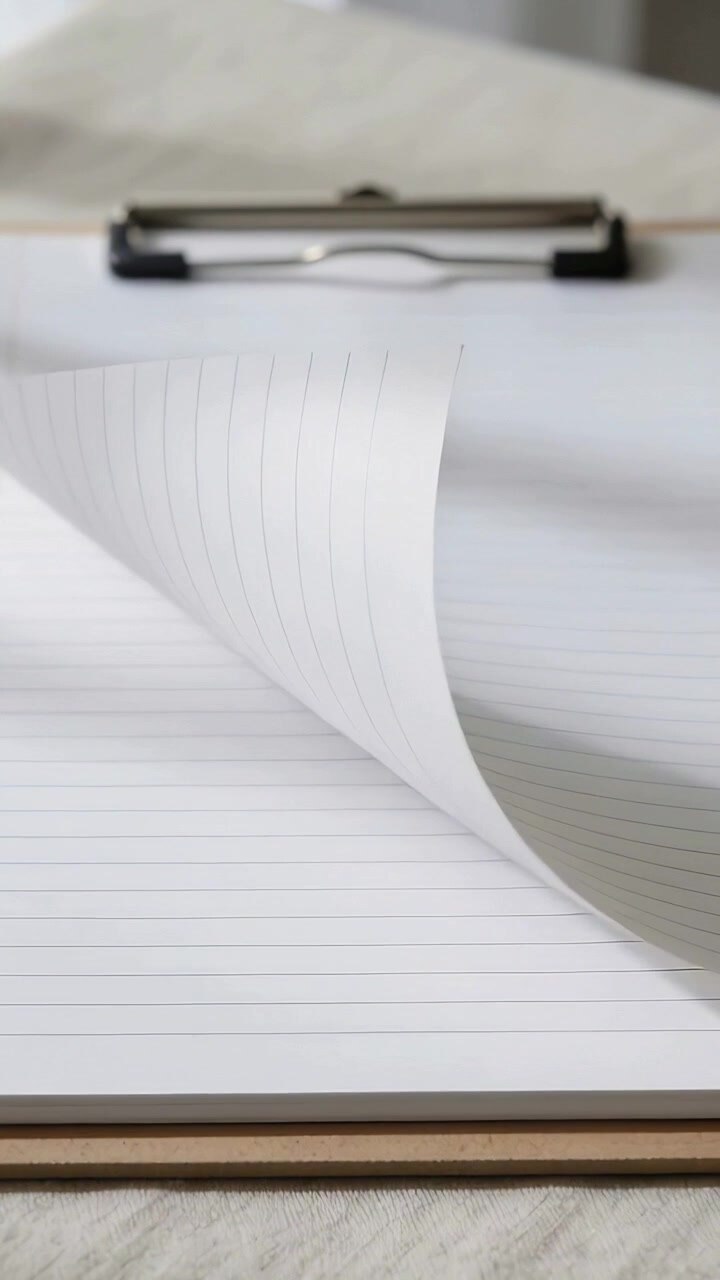 Vertical video: Flipping lined page on clipboard curling from corner by draft on cloth, metal clip