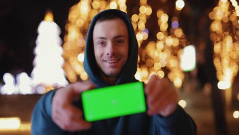 man shows empty green screen at night