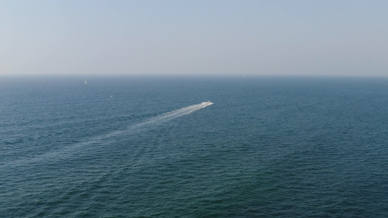 скоростной катер проносится на очень большой скорости над прозрачными спокойными голубыми водами, оставляя за собой длинную белую полосу средиземного моря в солнечный день