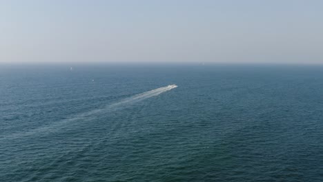 Speedboat-travels-at-very-high-speed-over-the-clear-calm-blue-waters-as-it-leaves-behind-a-long-white-stripe-of-the-Mediterranean-on-a-sunny-day