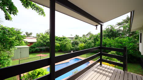 open patio walkway with stairs leads down to backyard pool fenced in on grassy lawn with natural rock drainage