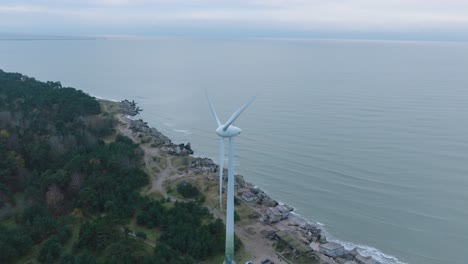 estableciendo una vista aérea de los edificios fortificados abandonados a la orilla del mar en los fuertes del norte de karosta en la playa del mar báltico en liepaja, día nublado, turbina eólica, disparo de órbita de avión no tripulado
