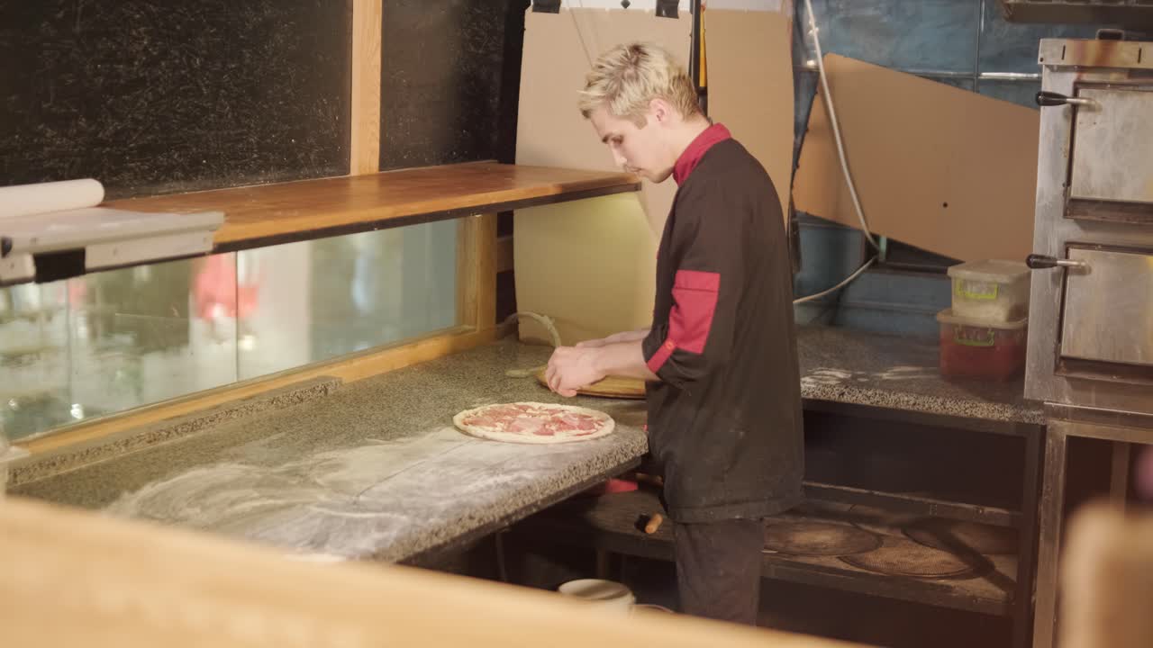 hombre cocinando pizza en la cocina de un restaurante