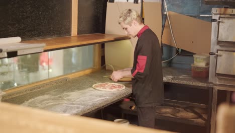 man cooking pizza in the kitchen of restaurant