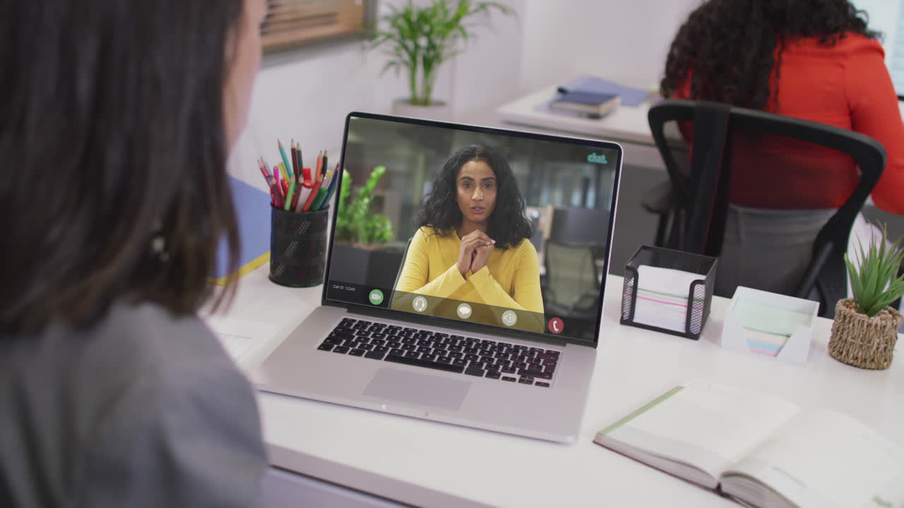Biracial businesswoman using laptop for video call with biracial business colleague
