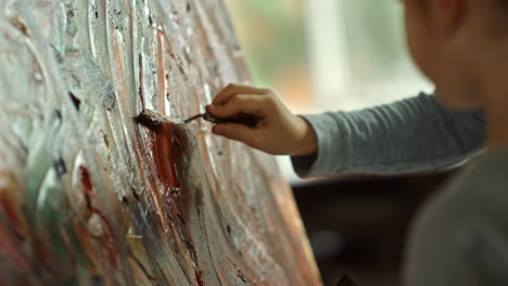 Child-hand-holding-painting-tool-in-art-studio