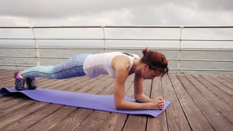 young woman training on the beach in front of the ocean. morning gymnastic. elbow and hand plank exercise. healthy active