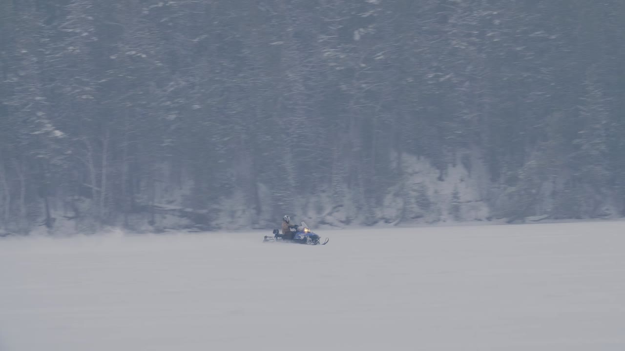 Snowmobilers speed across a vast winter landscape in Canada