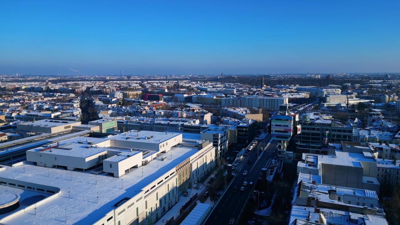 Berliinin kaupunkimaisema lumipeitteisine rakennuksineen ja vilkkaine katuineen, esitellen eurooppalaista kaupunkiarkkitehtuuria kirkkaana talvipäivänä. Uskomaton ilmakuva, laskeutuva panoraama dronella.