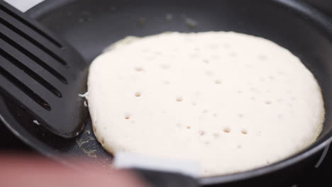 pancake pikelet flipped on a frying pan outdoors, slow motion