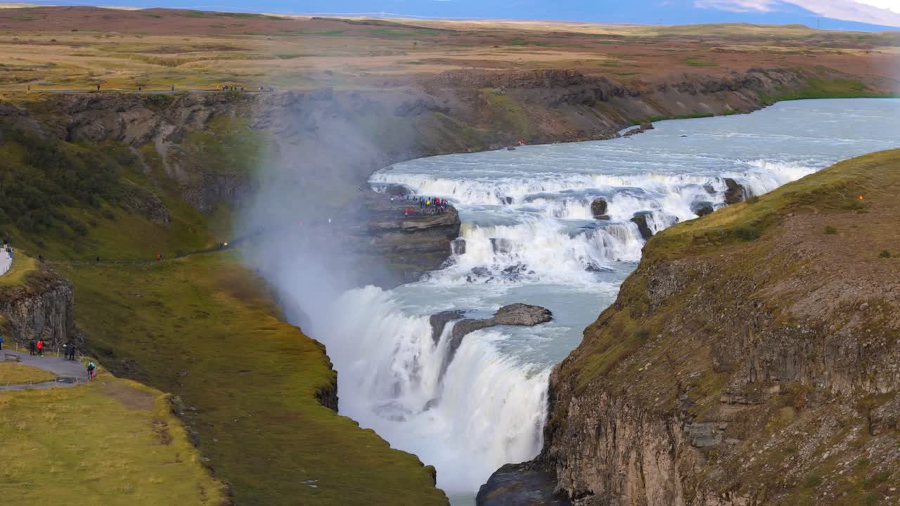 una toma aérea de turistas en las cataratas de gullfoss que fluyen a través del cañón