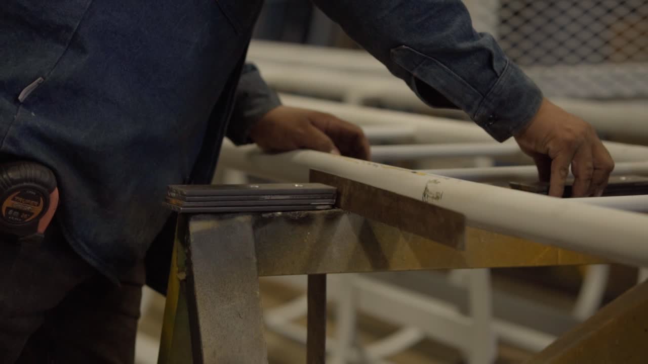 Slow motion shot of a worker adjusting a metal ladder inside a workshop environment during industrial assembly